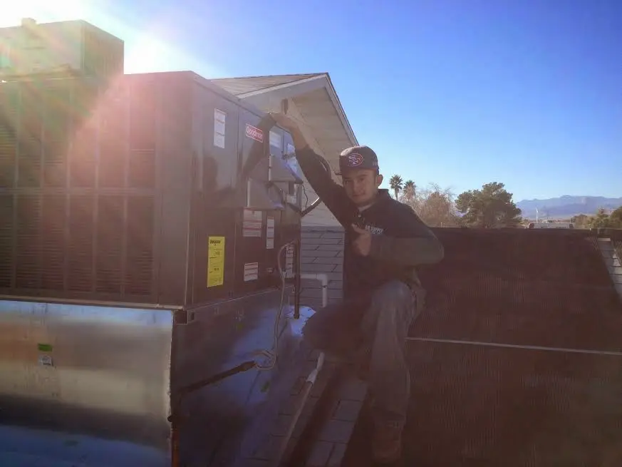 HVAC technician performing Air Duct Cleaning on a rooftop unit in Chesapeake